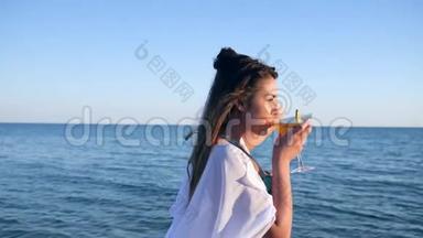 肖像美丽的女孩在大海上眺望远方，畅饮